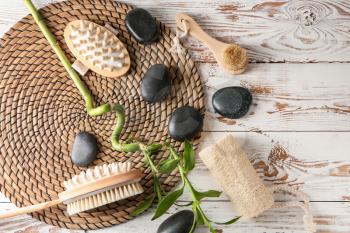 Massage brushes with spa stones on white wooden background�