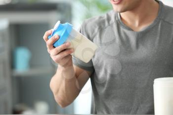 Sporty man with protein shake at home�