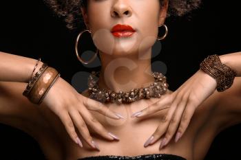 Beautiful African-American woman with bijouterie on dark background�