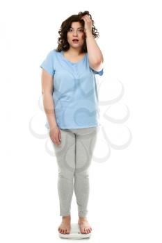Shocked overweight woman standing on scales against white background�