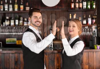 Young waiters giving each other high-five in restaurant�