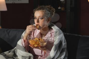 Beautiful young woman eating unhealthy food at night�