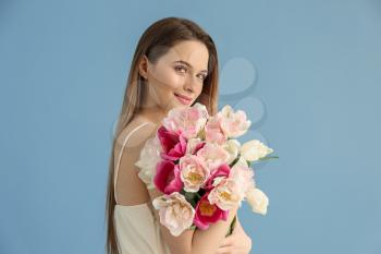 Young woman with bouquet of beautiful tulips on color background�