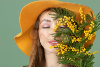 Beautiful young woman with bouquet of mimosa flowers on color background�
