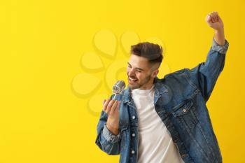 Handsome male singer with microphone on color background�