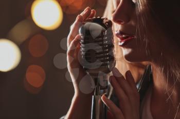 Beautiful female singer with microphone on stage, closeup�