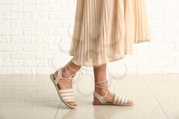 Stylish young woman in shoes near white brick wall�