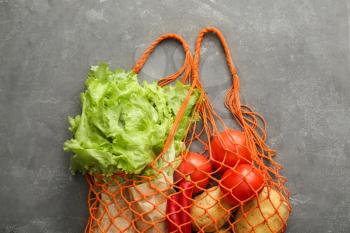 Fresh vegetables with mesh shopping bag on grunge background. Zero waste concept�