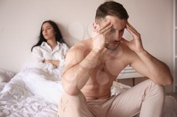 Young sad man sitting on bed after quarrel with wife�