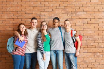 Group of teenagers near brick wall�