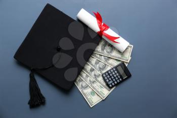 Mortar board with diploma, money and calculator on grey background. Concept of high school graduation�