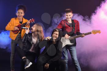 Band of teenage musicians on dark background�
