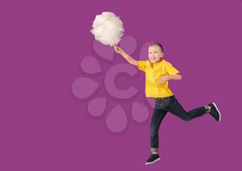 Jumping little boy with cotton candy on color background�