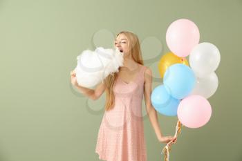 Beautiful woman with cotton candy and air balloons on color background�