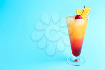 Glass of Tequila Sunrise cocktail on color background�