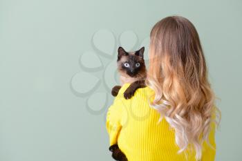 Young woman with cute Thai cat on color background�