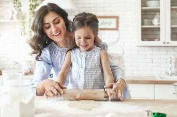 Happy mother with daughter preparing cookies in kitchen at home�