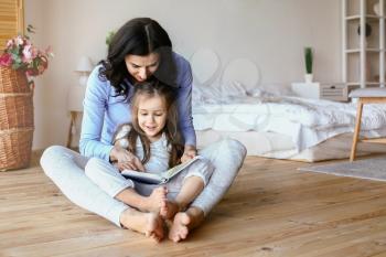 Happy mother with daughter reading book at home�