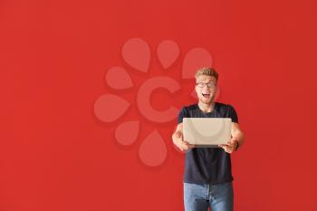 Happy young man with laptop on color background�