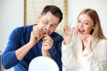 Couple flossing teeth at home�