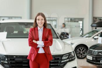Saleswoman in modern car showroom�