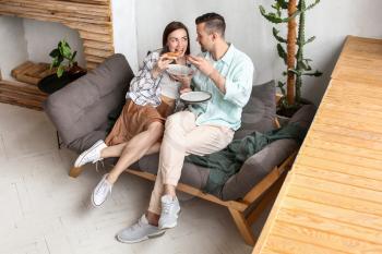 Happy couple eating tasty pizza at home�