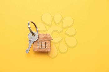 Key with trinket in shape of house on color background�