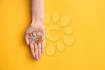 Female hand with key from house on color background�