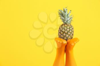 Legs of beautiful young woman in tights and pineapple on color background�
