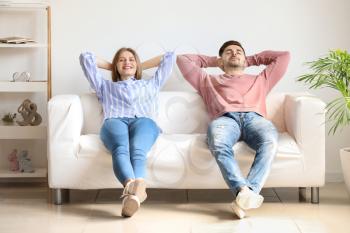 Happy young couple resting together on sofa at home�