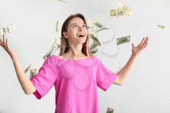 Happy young woman and falling dollar banknotes on white background�