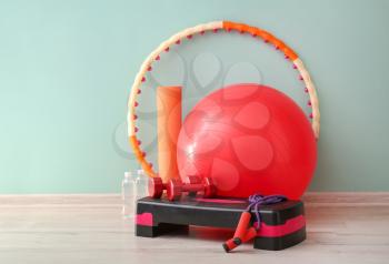 Set of sports equipment with fitness ball near color wall�
