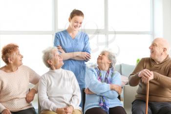 Young caregiver with group of senior people in nursing home�