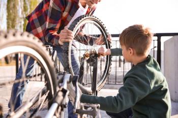Father and his son repairing bicycle outdoors�