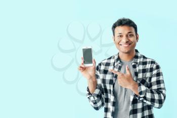 Handsome man with mobile phone on color background�