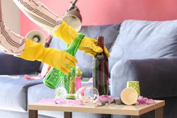 Woman cleaning room in terrible mess after party�
