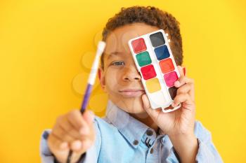 Cute little African-American artist on color background�