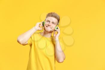 Portrait of happy young man listening to music on color background�