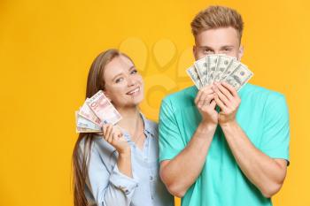 Happy couple with money on color background�