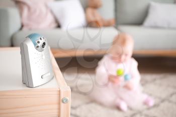 Modern baby monitor on table in room with little child�