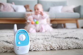 Modern baby monitor on floor in room with little child�