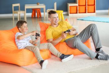 Portrait of father and son playing video game at home�
