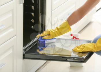 Woman cleaning oven at home�