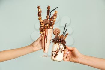Female hands with delicious freak shakes on grey background�
