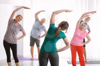 Senior people with young trainer doing exercises in nursing home�