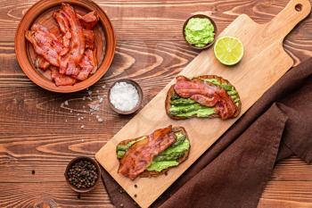 Tasty toasts with bacon on wooden table�