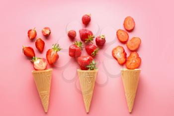 Waffle cones with ripe red strawberry on color background�