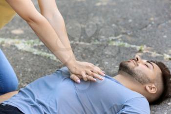 Woman giving CPR to unconscious man outdoors�