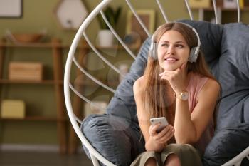 Young woman listening to audiobook at home�