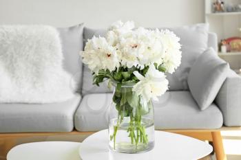 Vase with beautiful peony flowers on table in room�
